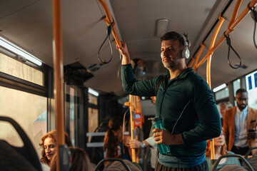 Man with headphones standing in a crowded bus