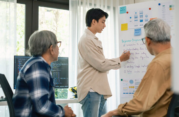 senior programmer bootcamlp,Asian young instructor guides senior learners through a programming on...