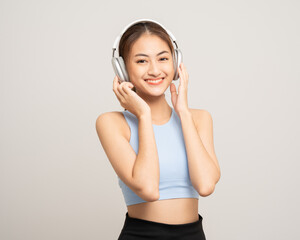 Naklejka premium Young beautiful asian woman with sportswear listen to music by headphone on isolated white background. Attractive Portrait sporty woman posing with cell phone