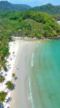 Koh Kood Island showcases stunning white sandy beaches bordered by clear turquoise waters. Gentle waves lap against the shore, while palm trees sway in the tropical breeze. Perfect for relaxation.