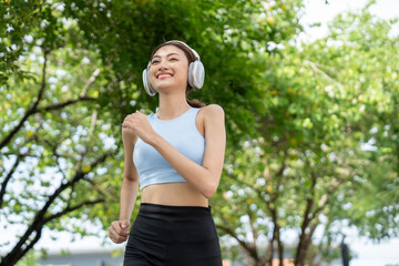 Happy slim beautiful woman wearing sportswear jogging in the park with sunrise. Young beautiful...