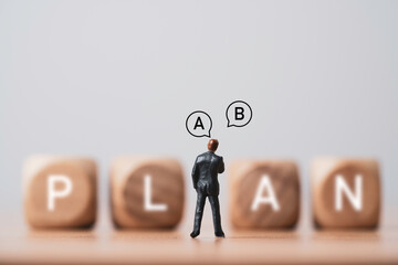 Businessman miniature figure standing  and  thinking with plan A and B for business strategy of...