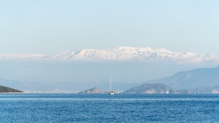 A sailboat float on Mediterranean sea in Fethiye, Turkey, with a stunning backdrop of snow-capped...