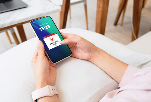 Emergency alert warning displayed on smartphone screen as symbols telling people to be careful. Technology concept