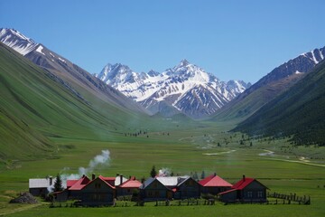A group of houses in a grassy field with mountains in the background