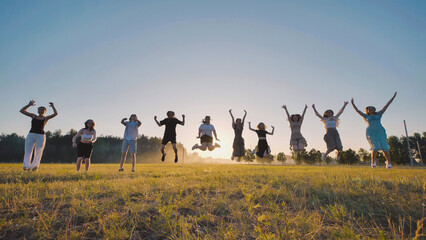 Happy high school students having fun during summer break, leaping with joy in a field at sunset