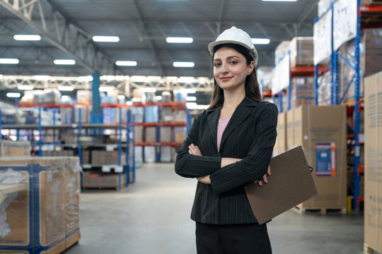 Portrait of confident woman business owner with clipboard and arms crossed inspecting, checking stock products at warehouse factory store. Logistics, Distribution Center concept - Powered by Adobe