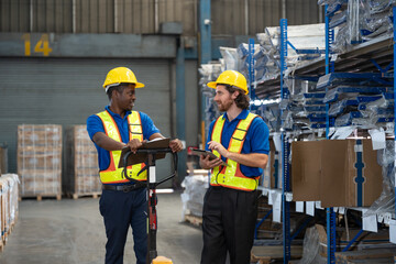 Two men warehouse worker wearing uniform and helmet safety standing using tablet checking stock...