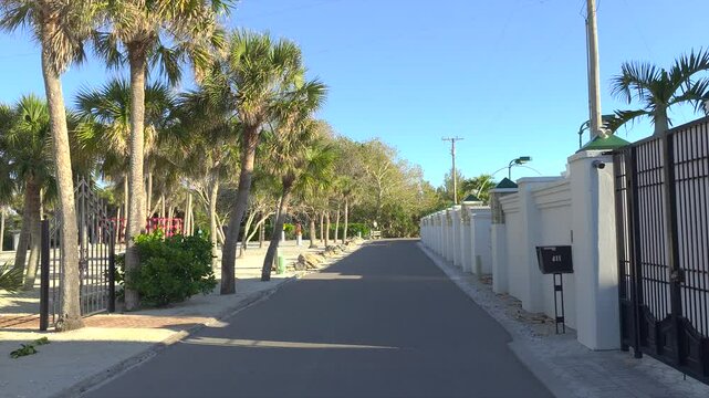 Driving on Florida scenic road. Car point of view of Casey Key coastal neighborhood with tropical nature and southern architecture.