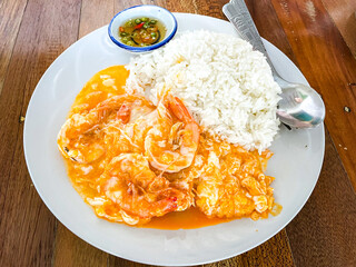 Creamy Omelet with Shrimps on Rice in white plate on wooden table