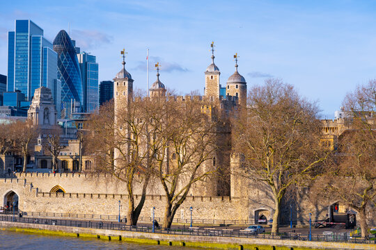 Visitors admire the Tower of London, a historic fortress on the River Thames, surrounded by modern skyscrapers in central London. The landmark showcases its iconic architecture and rich history.