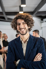 Smiling young businessman working inside modern office with the multiethnic team behind him - Concept of leadership and achieving goals - Focus on eyes - Vertical editing