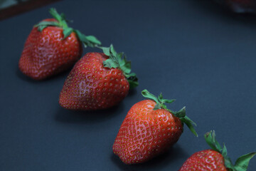 Large strawberries lie on a black base. Natural fruit, healthy nutrition.