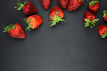 On a black background on top lies a juicy berry - strawberry. Space for text. Healthy eating and...