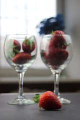 On a black background there are glasses filled with strawberries, in the foreground there is a juicy berry. The concept of healthy eating.