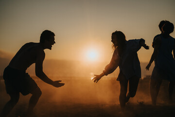 A group of friends interact joyfully outdoors during sunset, creating a warm and lively atmosphere....