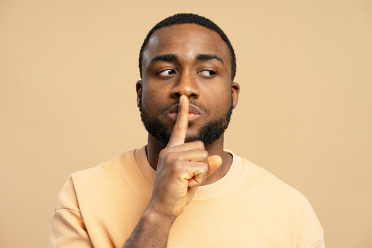 African American man showing silence sign with finger on lips