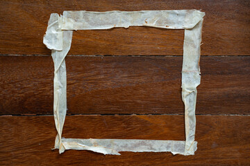 Square frame of used masking tape on wooden floor