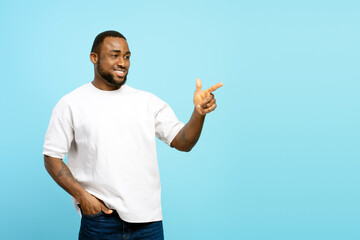 Smiling African American man pointing finger showing something on blue background