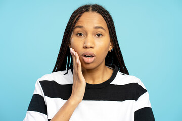 African American woman suffering from toothache touching cheek on blue background