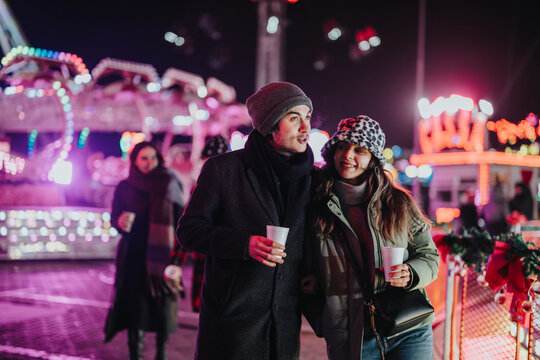 Friends spend time together at a nighttime holiday fair, enjoying the festive atmosphere with bright lights and cheerful vibes. Perfect depiction of friendship and holiday celebrations in winter.