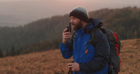 A lone traveler communicates via radio on a high mountain, surrounded by wild nature....