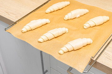 a tray of croissants in a home kitchen. making croissants at home. homemade baked goods. baking on...