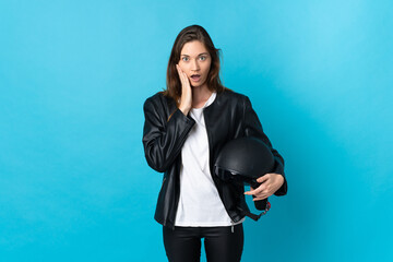 Young Ireland woman holding a motorcycle helmet isolated on blue background with surprise and...