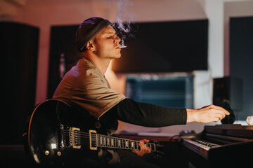A musician is seen enjoying a moment of creativity in a recording studio. With a guitar on his lap,...