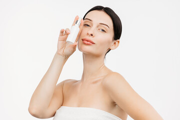 A young woman against a white background applies a moisturizing collagen emulsion. This moment...