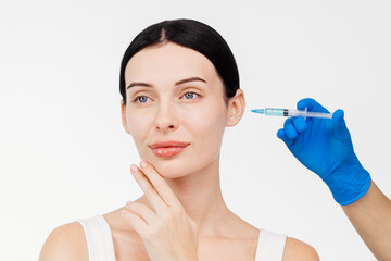 Beautiful young woman with a serene expression. Gloved hand holds a syringe. Cosmetology and...