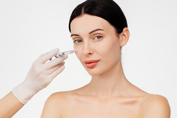 Beautiful young woman with a serene expression. Gloved hand holds a syringe. Cosmetology and...