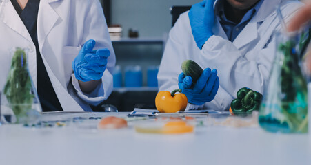 Team Asian scientists in a lab conducting food research using a microscope and lab equipment,...