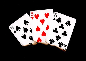 A hand of three burnt playing cards of the same value.