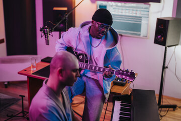 Diverse group of musicians working together on music production inside a professional studio. The...