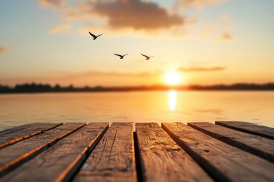 Wooden pier at sunset with birds flying over calm lake