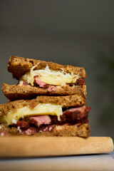 Two layers of a Reuben sandwich filled with corned beef, Swiss cheese, and sauerkraut, placed on a wooden board, highlighting a tasty meal perfect for lunchtime.