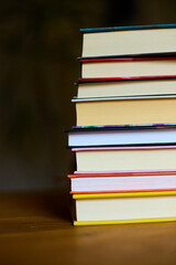 A collection of colorful books stacked neatly on a wooden table, evoking a sense of warmth and inviting readers to explore the stories within them.