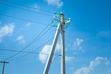 Electric cables on electric poles with a blue sky.