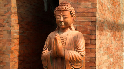An old red clay statue of Buddha standing on the street on the bali