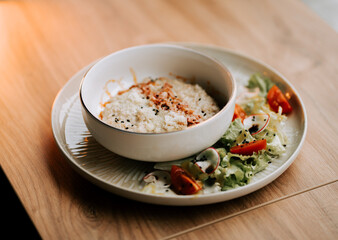 Savory oatmeal topped with fried bacon and parmesan on a wooden table