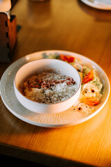 Savory oatmeal topped with crispy bacon and grated parmesan beside a fresh salad