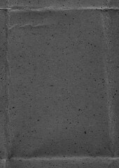 Close-up of dark, nearly black paper with pronounced vertical and horizontal creases intersecting...