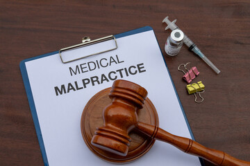 A legal document on medical malpractice is placed in a clipboard, set on a professional desk alongside a judge’s gavel, symbolizing legal and ethical accountability in the medical field.