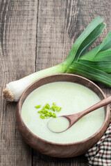 Creamy Leek Soup in wooden bowl on rustic table