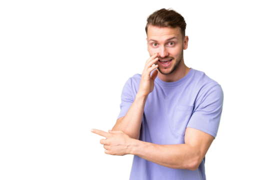 Young handsome caucasian man over isolated chroma key background pointing to the side to present a product and whispering something