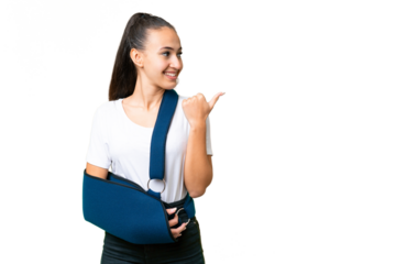 Young Arabian woman with broken arm and wearing a sling over isolated chroma key background pointing to the side to present a product