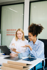 Fototapeta premium Female discussing new project with Female colleague. Young woman talking with young african woman