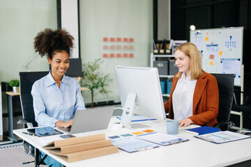 Obraz premium Female discussing new project with Female colleague. Young woman talking with young african woman