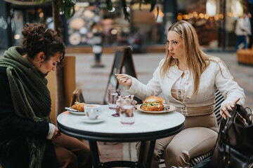 Two women sit at a cafe, engaging in a serious conversation while having lunch.